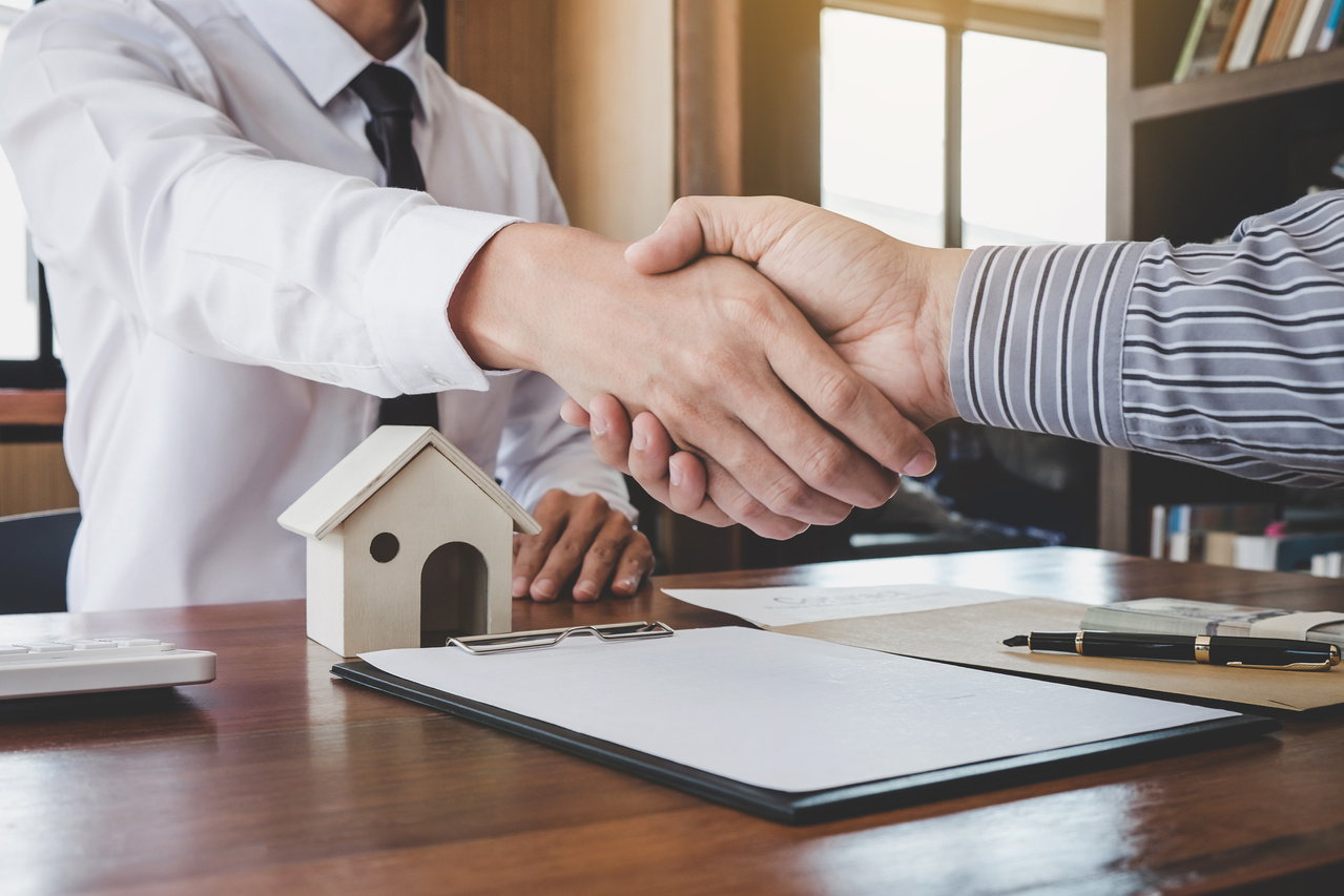 Real estate broker agent and customer shaking hands after signing contract documents for realty purchase, Bank employees congratulate, Concept mortgage loan approval